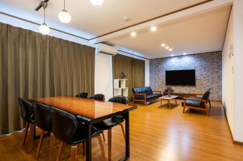 una sala da pranzo con tavolo, sedie e TV di neige furano Vacation rented house a Furano
