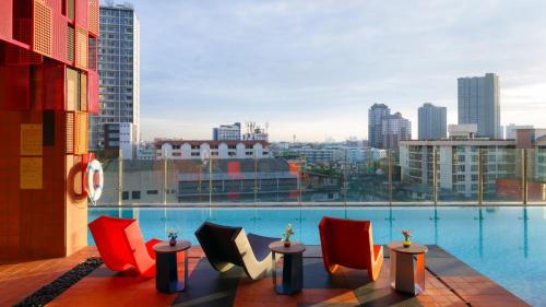 a view of a pool from a building with chairs at ibis Styles Bangkok Sukhumvit Phra Khanong in Bangkok