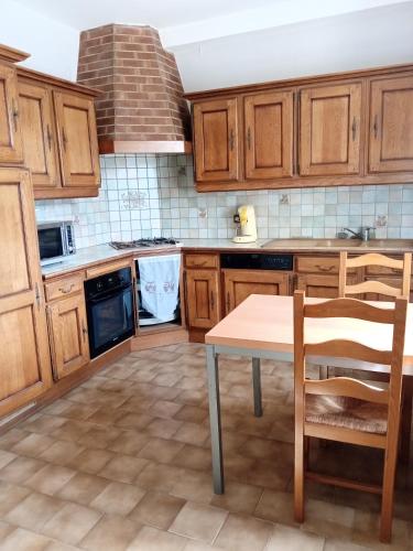une cuisine avec des armoires en bois et une table avec des chaises dans l'établissement Maison champêtre au coeur de la campagne, à Fontaines