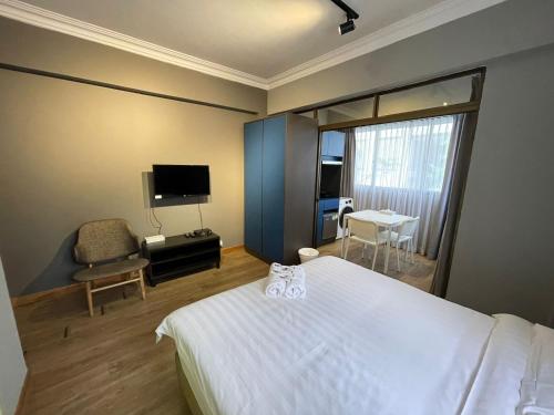 a hotel room with a bed and a chair and a television at Greatwood Residence at Devonshire in Singapore