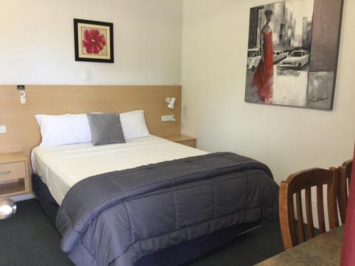 a bedroom with a bed and a picture of a woman at Ayrline Motel in Ayr