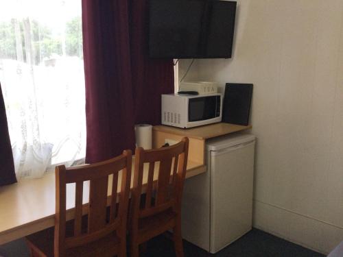 a room with a desk with two chairs and a microwave at Ayrline Motel in Ayr