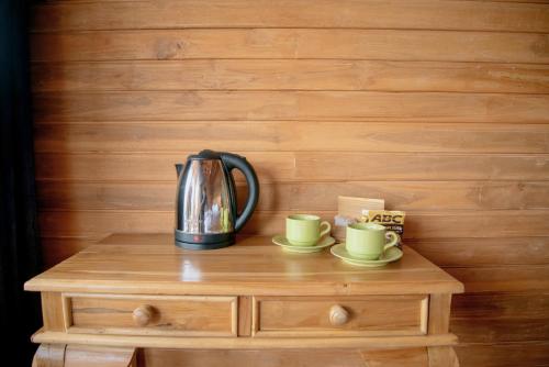 a coffee pot and two cups on a wooden table at Butterfly Villas Nusa Ceningan in Nusa Lembongan