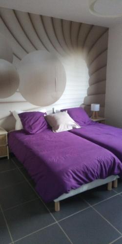 a bed with purple sheets and pillows in a room at la chambre du clos Barriant in Séreilhac