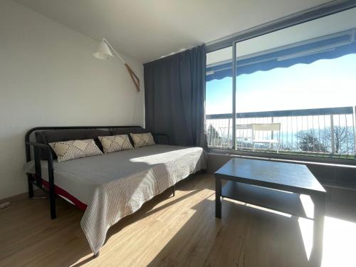 a bedroom with a bed and a table and a large window at PERCHOIR 1 : Studio haut de gamme et lumineux in Turckheim