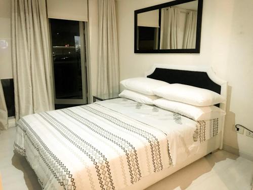 a bedroom with a bed with white sheets and a mirror at Azure Urban Resort and Residences by Rosary in Manila