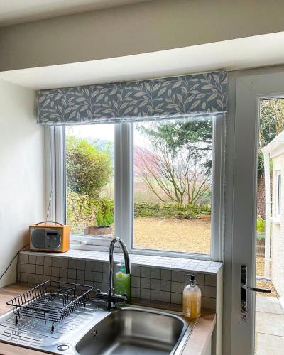 a kitchen window with a valance over a sink at Cotswold Coombe Cottage in Wotton-under-Edge
