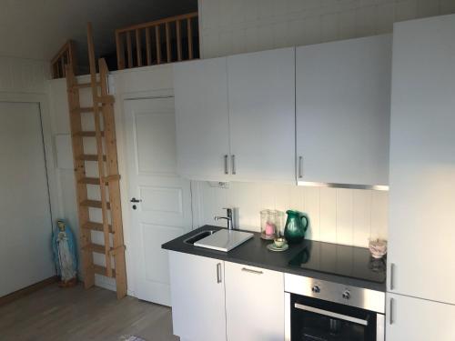 a kitchen with white cabinets and a sink at Lyseren waterfront cabin in Omberg