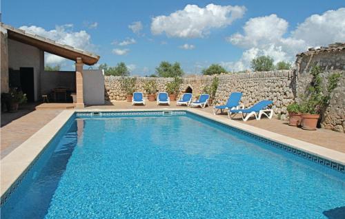 a swimming pool with blue chairs and a stone wall at Beautiful Home In Porreres With 5 Bedrooms, Private Swimming Pool And Outdoor Swimming Pool in Porreres