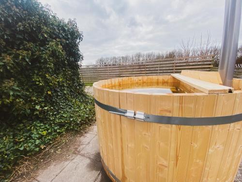 a wooden barrel sitting on a sidewalk next to a hedge at Slava Hygge House in Nakskov