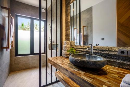 La salle de bains est pourvue d'un lavabo en pierre sur un comptoir en bois. dans l'établissement Shanti Sawah Ubud Villa, à Ubud