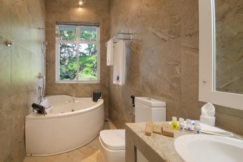 a bathroom with a tub and a toilet and a sink at Waters Spring in Kandy