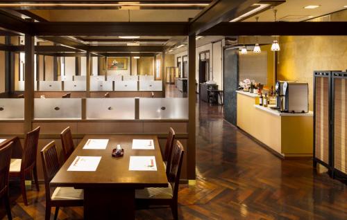 a dining room with a table and chairs and a kitchen at Kishigon Ryokan in Shibukawa