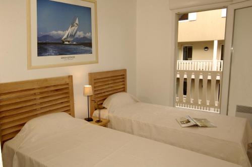 Lagrange Vacances - Villa d'Este في أركاشون: غرفة نوم بسريرين وقارب شراعي على الحائط