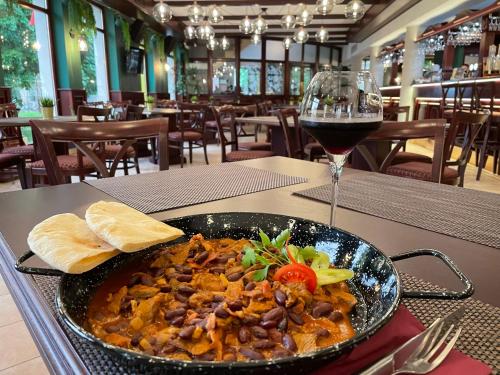 a bowl of food on a table with a glass of wine at Chicago Vendégház in Szentes