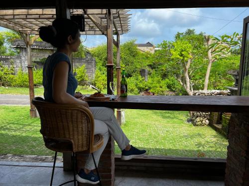 a woman sitting at a table looking out a window at PINOKKIO B&B Restaurant in Jimbaran