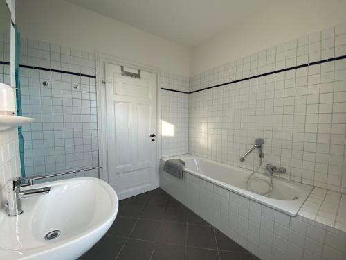 a white bathroom with a tub and a sink at Ferienhaus Lütt Hüsken in Lemgo