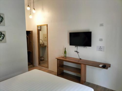 a bedroom with a bed and a tv on a wall at Suites by Eco Hotel El Nido in El Nido