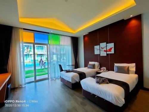 a hotel room with two beds and a window at Southern Airport Hotel Hatyai in Hat Yai