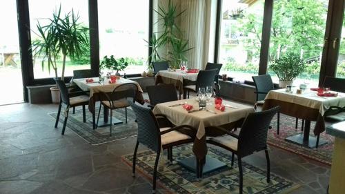 - une salle à manger avec des tables, des chaises et des fenêtres dans l'établissement Landhaus Weingut, à Cornaiano