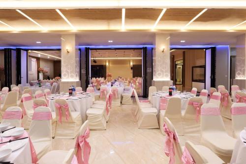 a banquet hall with white tables and white chairs at Southern Airport Hotel Hatyai in Hat Yai