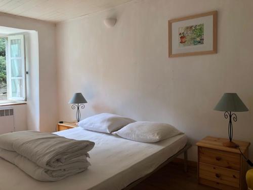 a bedroom with a bed and two lamps and a window at Les Volets Verts in Miraval-Cabardès