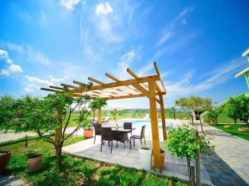 a patio with a wooden pergola and a table and chairs at Lovely apartment with swimming pool in Ljubač