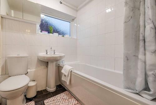 a bathroom with a toilet and a sink and a tub at Lovely 2 Bedroom Apartment with fireplace in Manchester