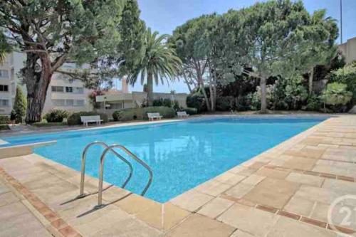 une grande piscine avec des arbres en arrière-plan dans l'établissement GOLFE JUAN Studio dans résidence avec piscine, à Vallauris