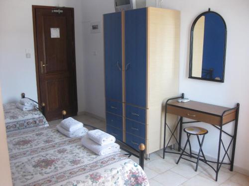 a bedroom with two beds and a dresser and a desk at Calypso Hotel in Lipsoi