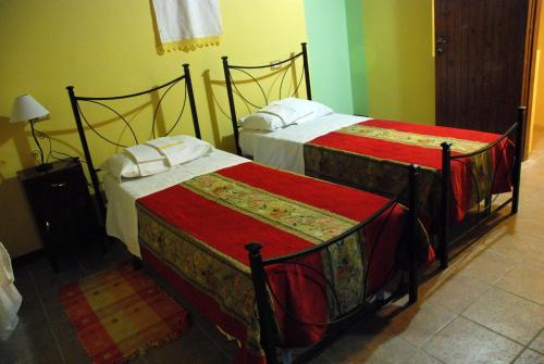 two beds in a hotel room with red sheets at Country House Al Faraone in Poggio Picenze