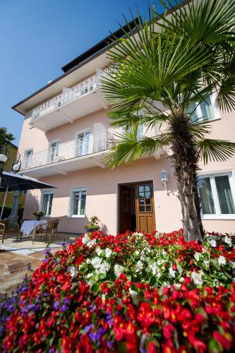 a building with a palm tree and flowers in front of it at Villa Auguste in Pörtschach am Wörthersee