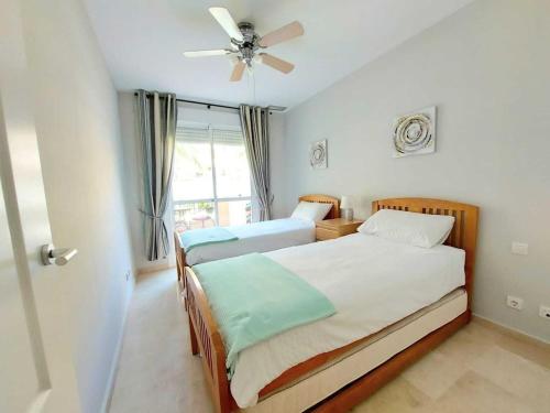 a bedroom with two beds and a ceiling fan at Duquesa Fairways, a spacious apartment with fabulous views and facilities in Manilva