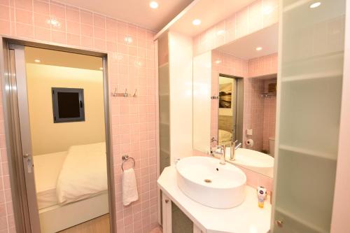 a pink bathroom with a sink and a mirror at Kai Place Oren's in Eilat