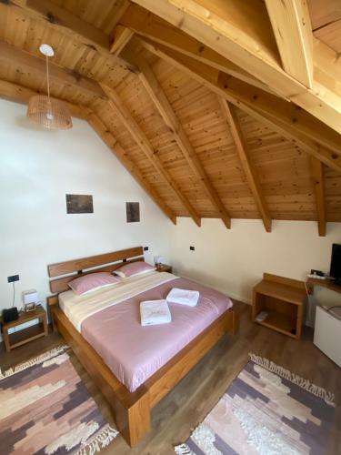 a large bed in a room with wooden ceilings at JOEN Village in Librazhd