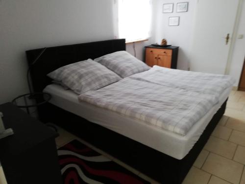 Bett mit schwarzem Rahmen und weißer Bettwäsche in der Unterkunft Ferienwohnung Tensfeldt in Lübben