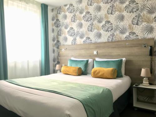 a bedroom with a large bed with two yellow pillows at Boutique Hôtel d'Orbigny Chatelaillon - La Rochelle in Châtelaillon-Plage