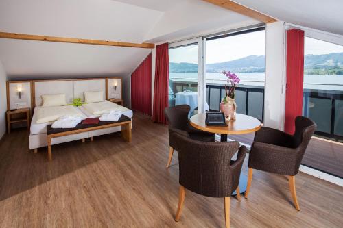 グムンデンにあるLandhotel Grünberg am Seeのベッドルーム1室(ベッド1台、テーブル、椅子付)