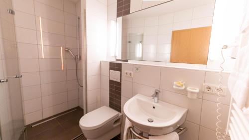 a bathroom with a sink and a toilet and a mirror at Hotel Christine in Radolfzell am Bodensee