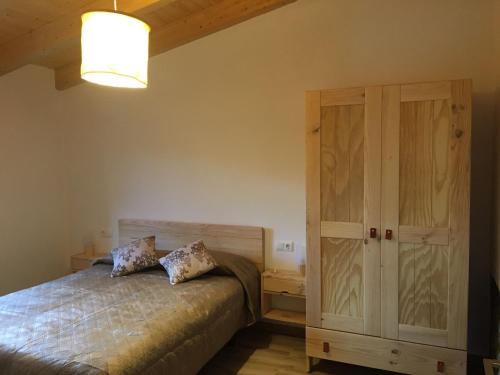 1 dormitorio con 1 cama y armario de madera en Casa Mestres, en Pujalt