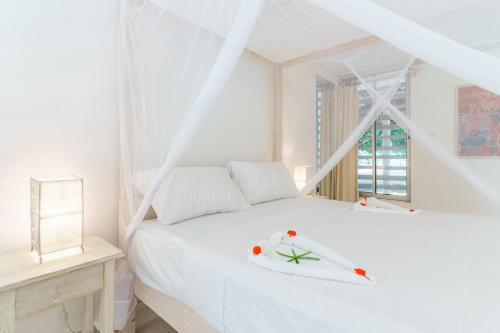 a white bedroom with a bed and a window at Flamboyant Diani Beach in Diani Beach