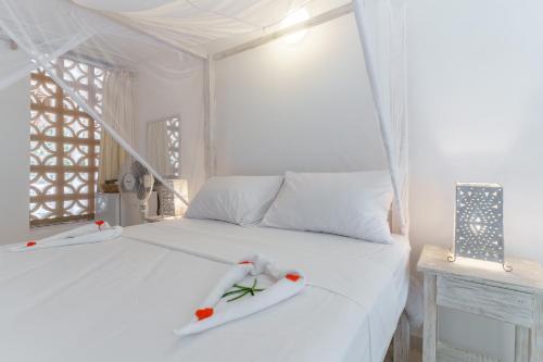 a white bed with two white towels on it at Flamboyant Diani Beach in Diani Beach