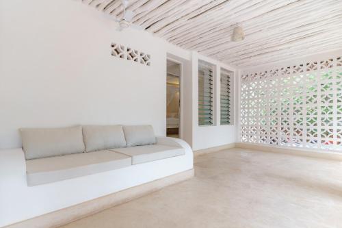 a white living room with a couch and a window at Flamboyant Diani Beach in Diani Beach