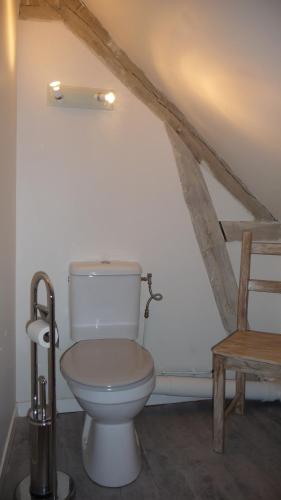 une salle de bain avec toilettes et une chaise en bois dans l'établissement La Grange du Couvent, à Sarlat-la-Canéda