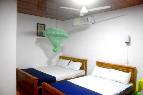 a room with two beds and a green lamp at Wilpattu Lakwin Guest in Pahala Maragahawewa