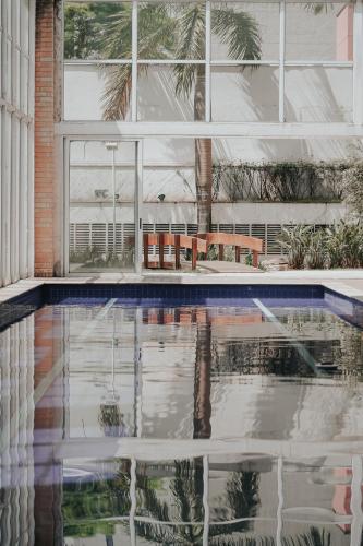 a swimming pool in a house with a reflection in the water at Duplex NYC Berrini - 1506 in Sao Paulo