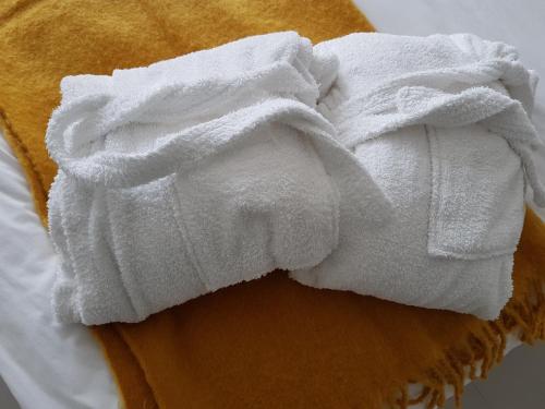 a pile of white towels on top of a bed at Petite Anchorage in Christchurch