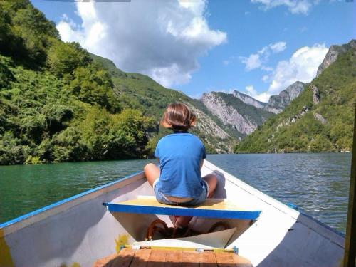 una mujer sentada en un bote en un lago en Agroturizem Hotel Vila Franceze, en Koman