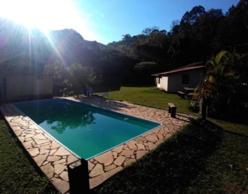a swimming pool in a yard with the sun shining at pousada macieiras in Paty do Alferes