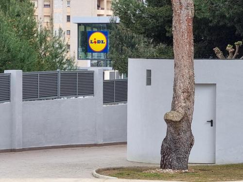 a tree next to a white wall with a door at Pinar de GARRUCHA in Garrucha